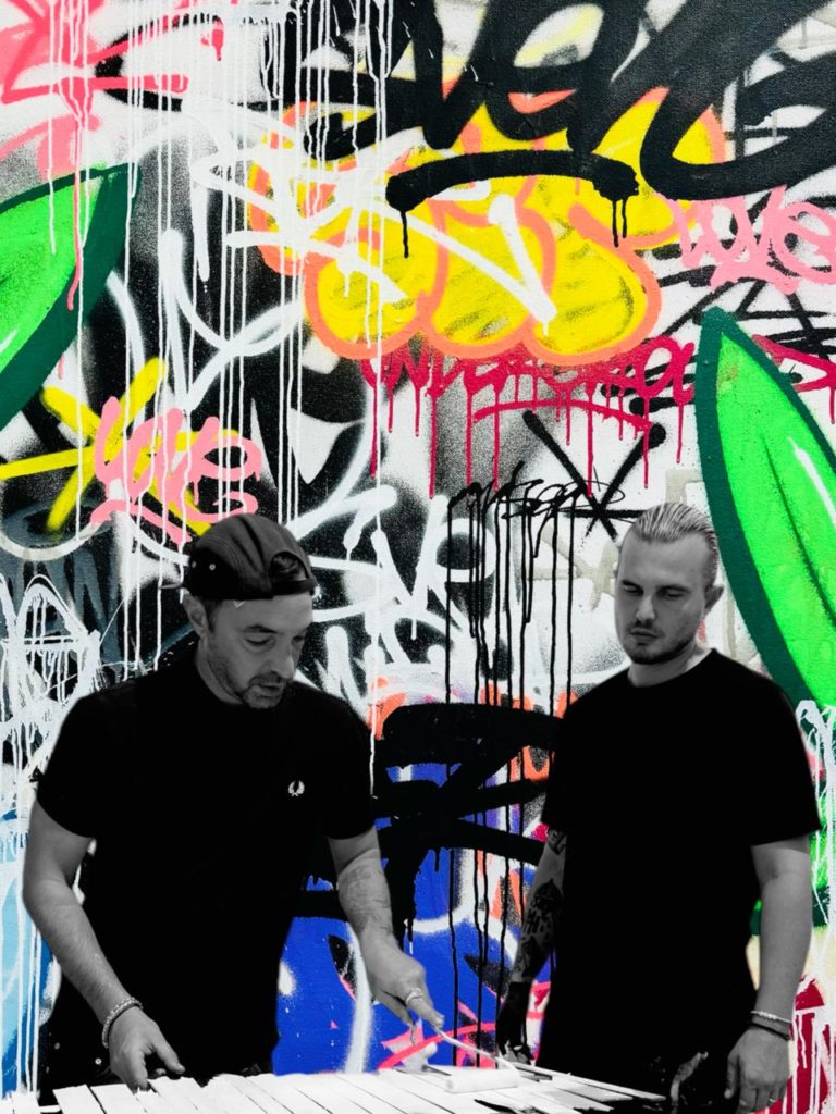 Sven et Onemizer posant devant une fresque pour l'exposition Frères d'Art